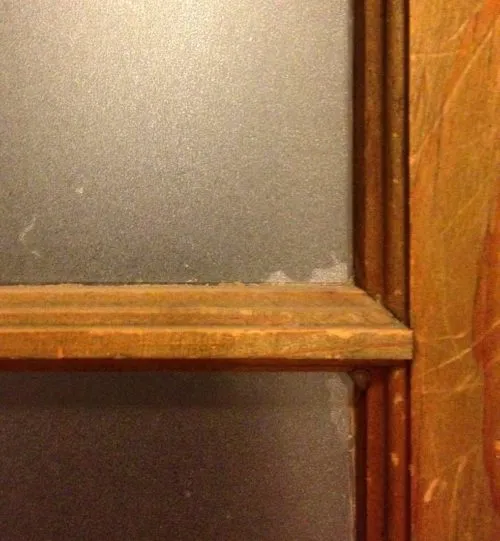Detailed view of a window pane covered with frosted window film, showing minor installation flaws
