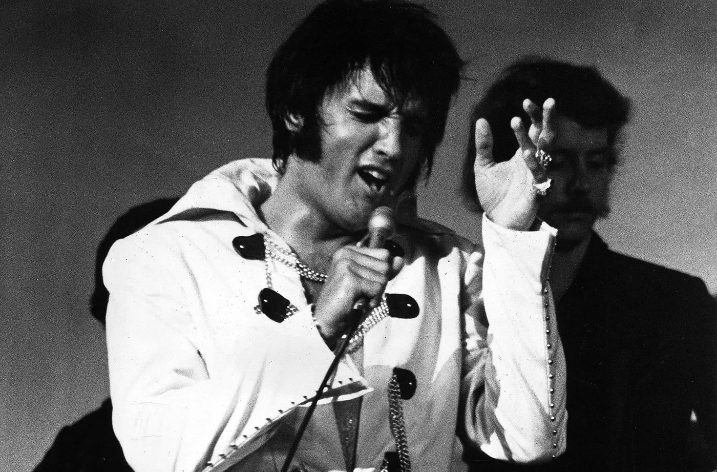 Elvis Presley performing on stage, wearing a sequined jumpsuit during a concert