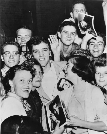 Elvis Presley surrounded by an enthusiastic group of fans in Amarillo, Texas on October 13, 1955, capturing the early fervor.