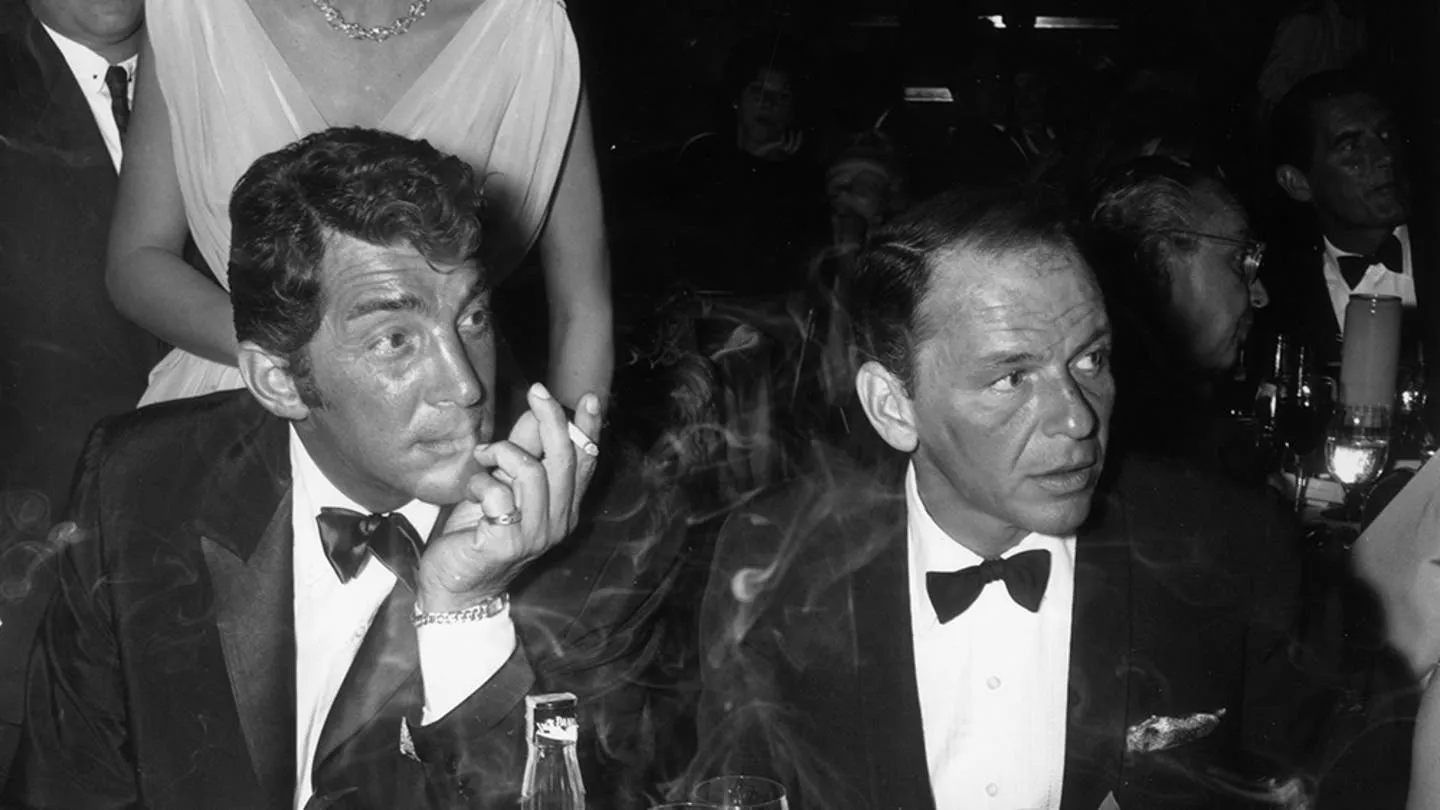 Frank Sinatra and Dean Martin looking concerned at a party.