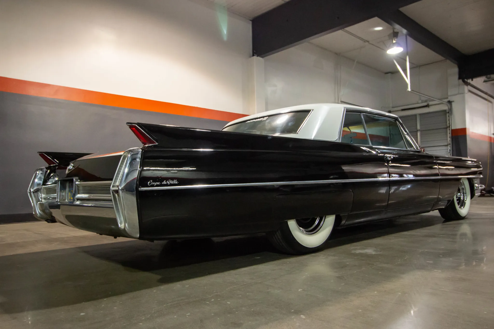 Front three-quarter view of the 1964 Cadillac Coupe DeVille in black with a white pearl roof
