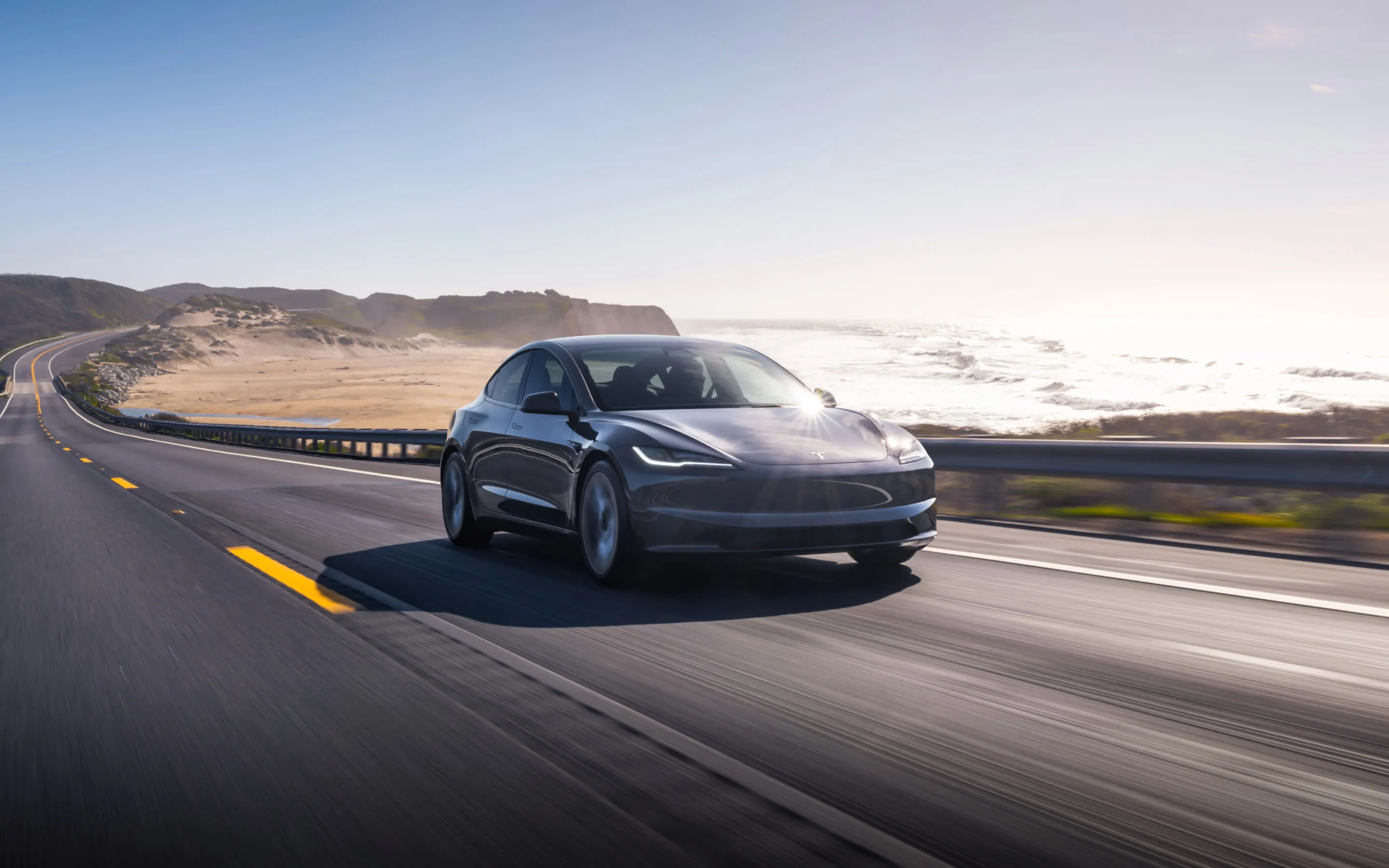 Front view of a white Tesla Model 3 parked on a scenic road