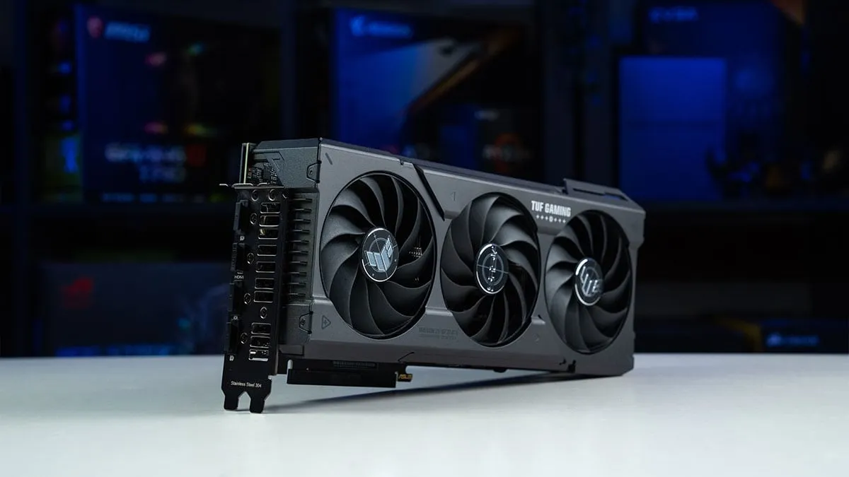 High-end AMD RX 7600 XT graphics card with triple-fan cooler on a desk against a background of computer hardware.