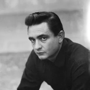 Johnny Cash in his signature black attire, holding a guitar on stage