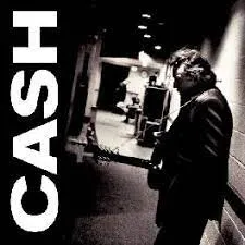 Johnny Cash on stage with an acoustic guitar, with a focused expression, wearing his signature black attire.