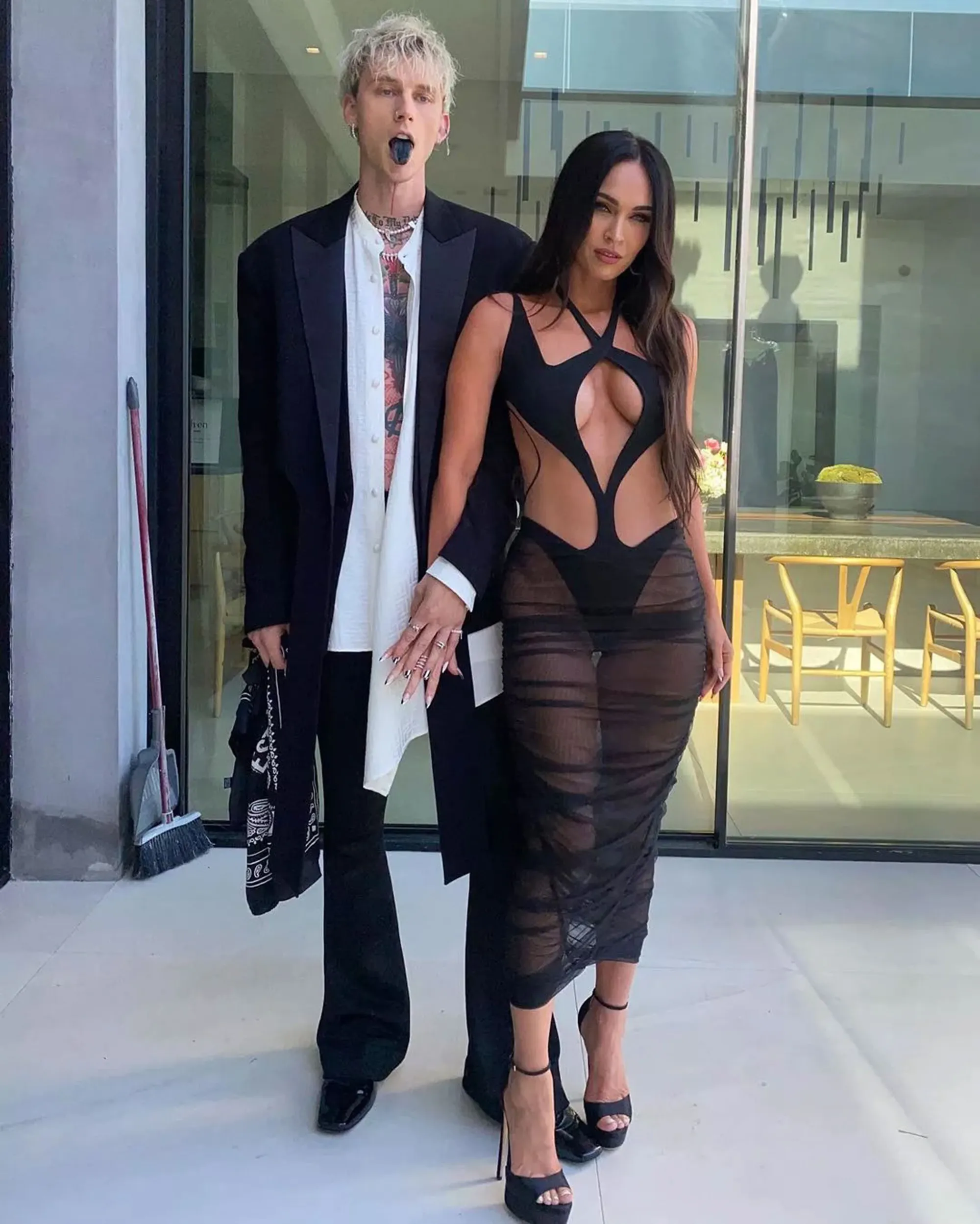 Machine Gun Kelly and Megan Fox posing, MGK with a dyed black tongue.