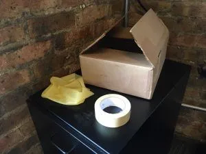 Materials for the Jackbox Games logo costume: a cardboard box, bald cap, and tape.