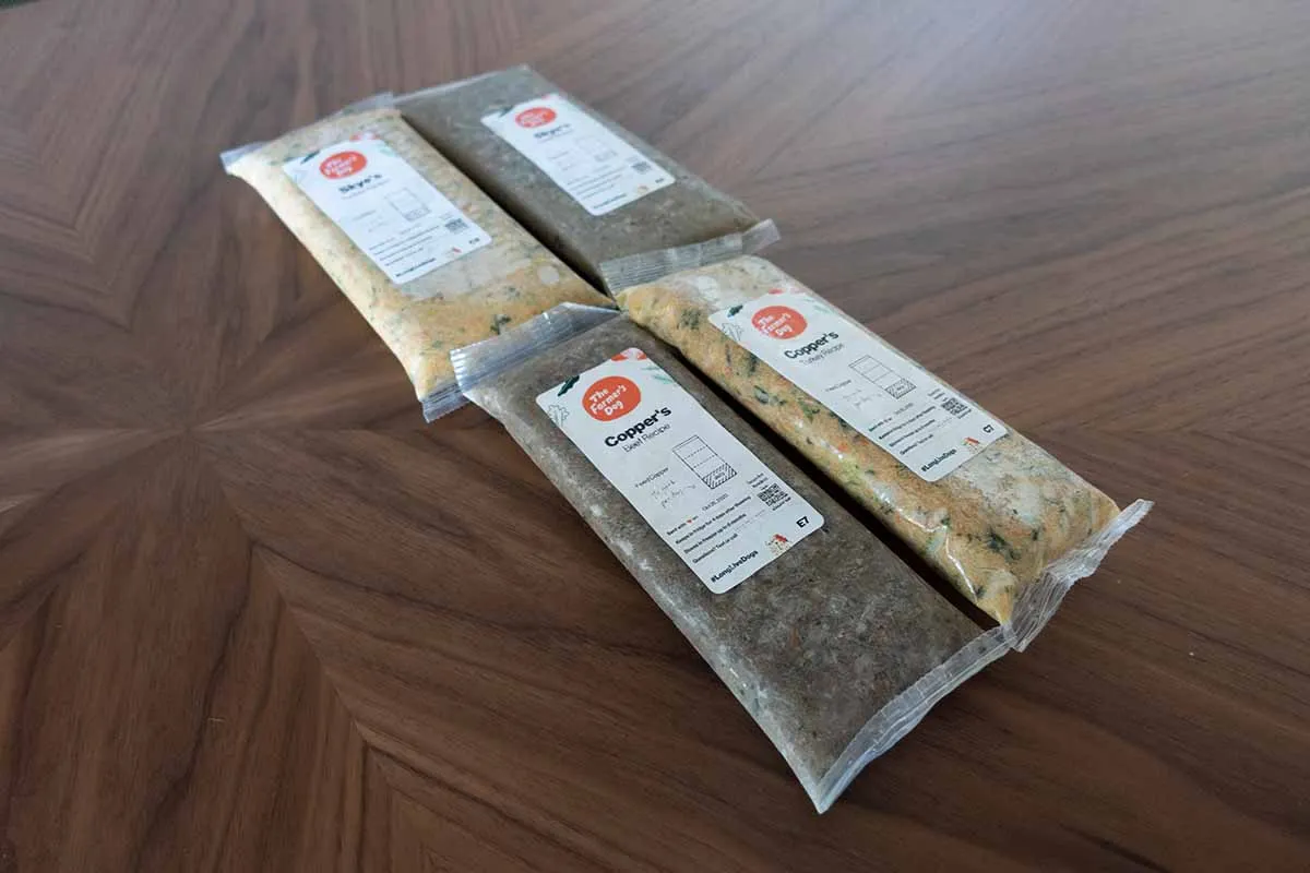 Packages of The Farmer's Dog food stacked, implying the quantity needed and potential cost