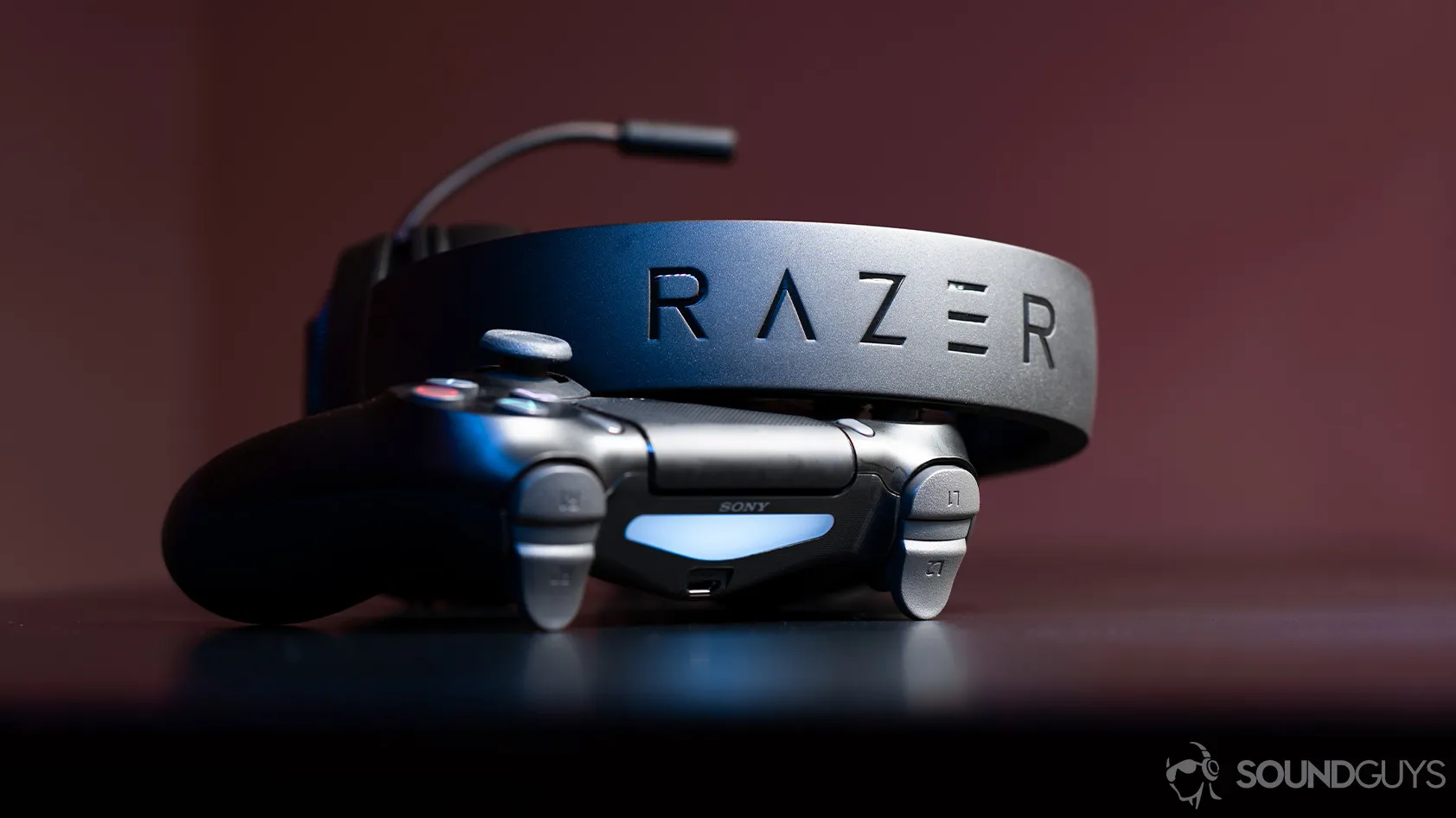 Razer Kraken X headset leaning against a PS4 controller, showcasing the headband with the Razer logo.