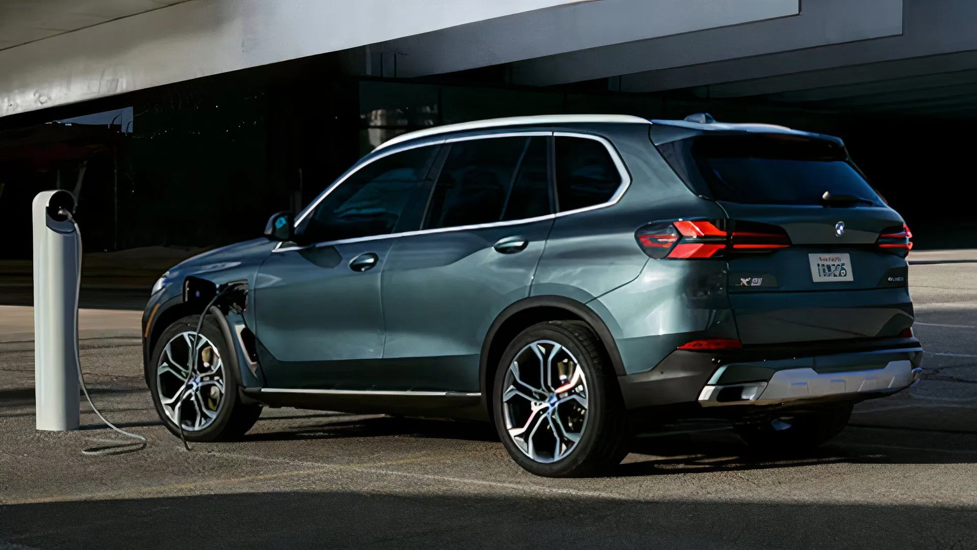 Rear three-quarter view of a dark green 2025 BMW X5 xDrive50e