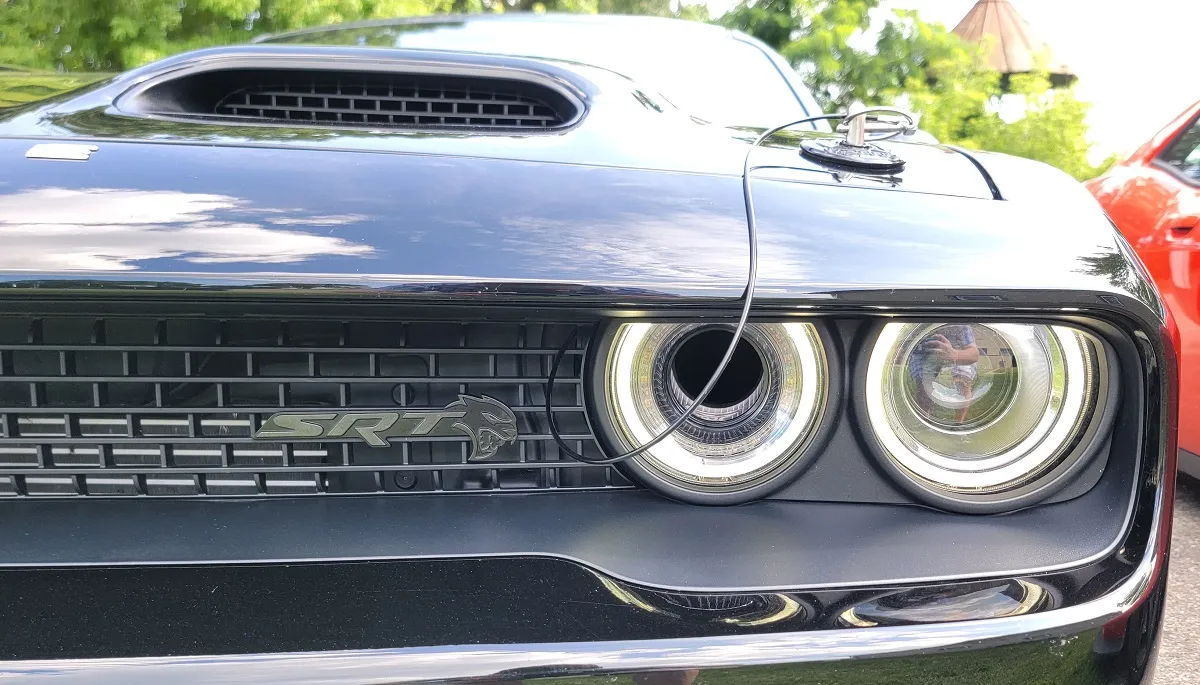 Rear three-quarter view of the 2023 Dodge Challenger Black Ghost in motion, showcasing its distinctive white tail stripe against the black paint.