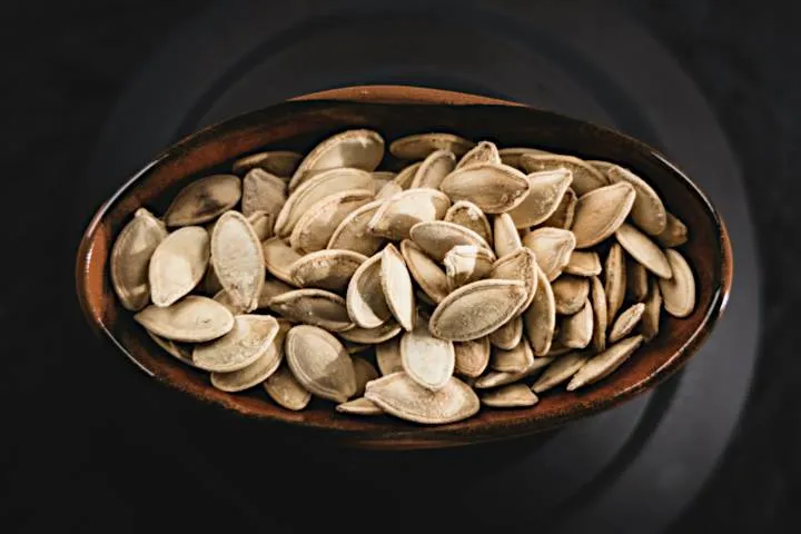 Roasted watermelon seeds in a small white ceramic bowl, a clean and unique gaming snack