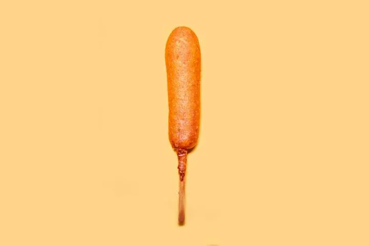 Several crispy corn dogs arranged on a tray, a convenient and filling gaming snack