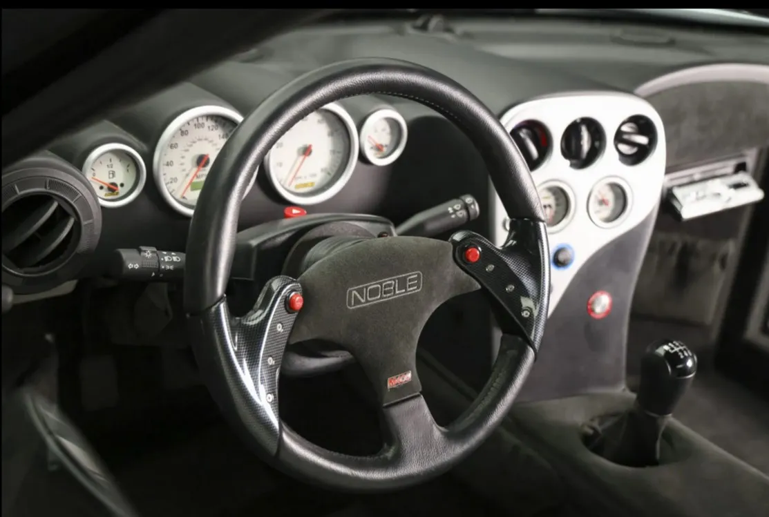 Side profile of a red 2006 Noble M400, revealing its compact dimensions and purposeful design