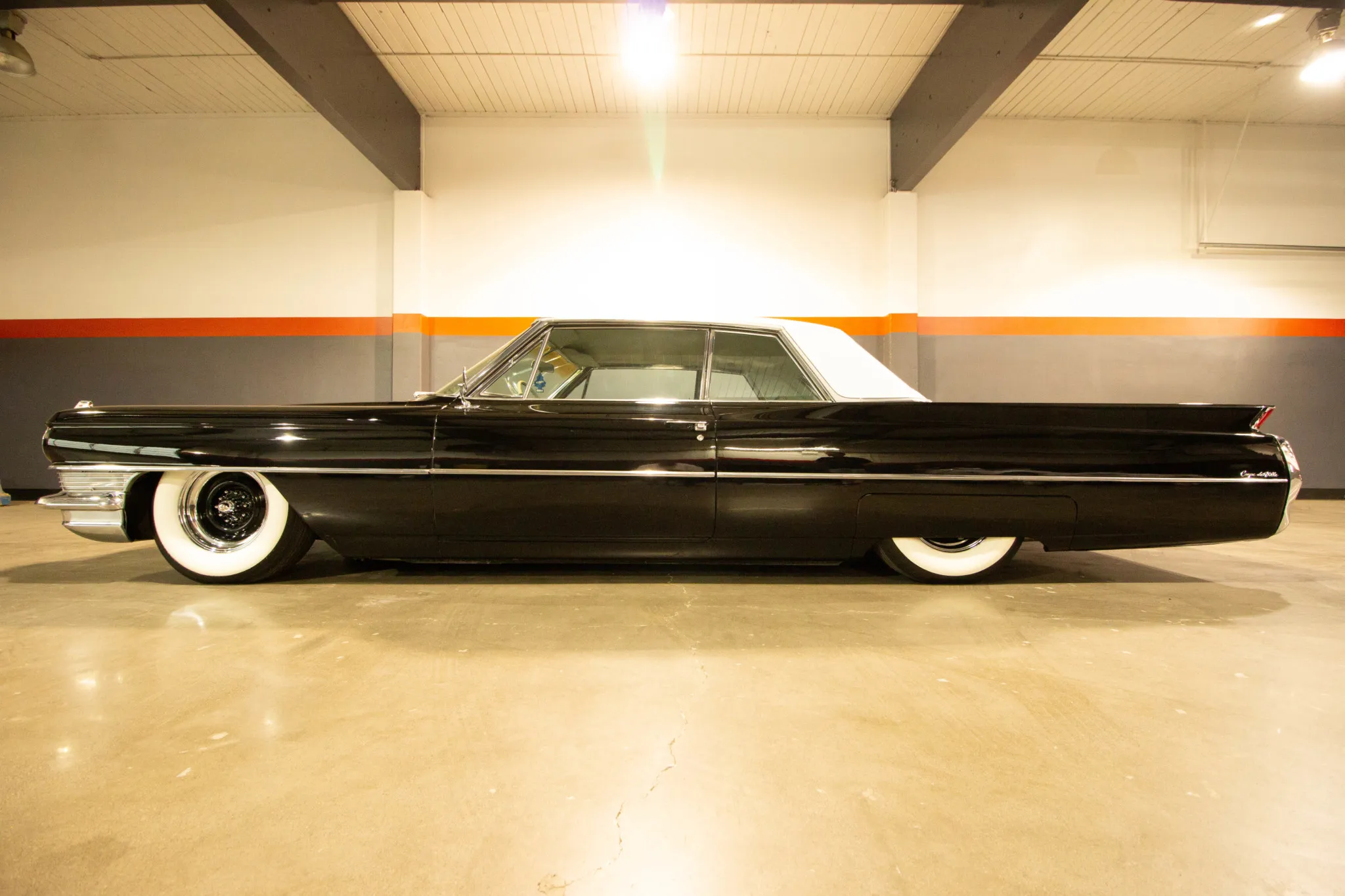 Side profile of the 1964 Cadillac Coupe DeVille showcasing its lowered stance and whitewall tires