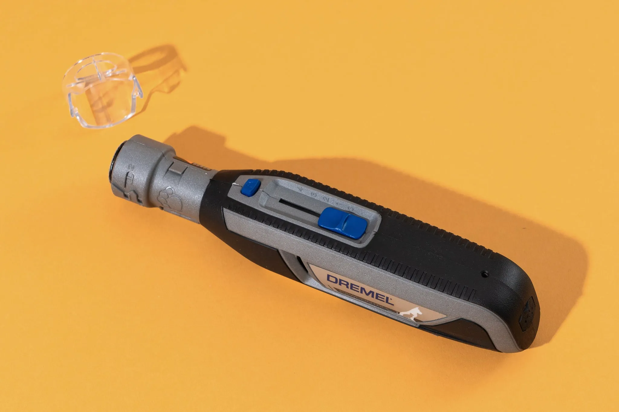 The Dremel grinder resting on a yellow background with its cap off.