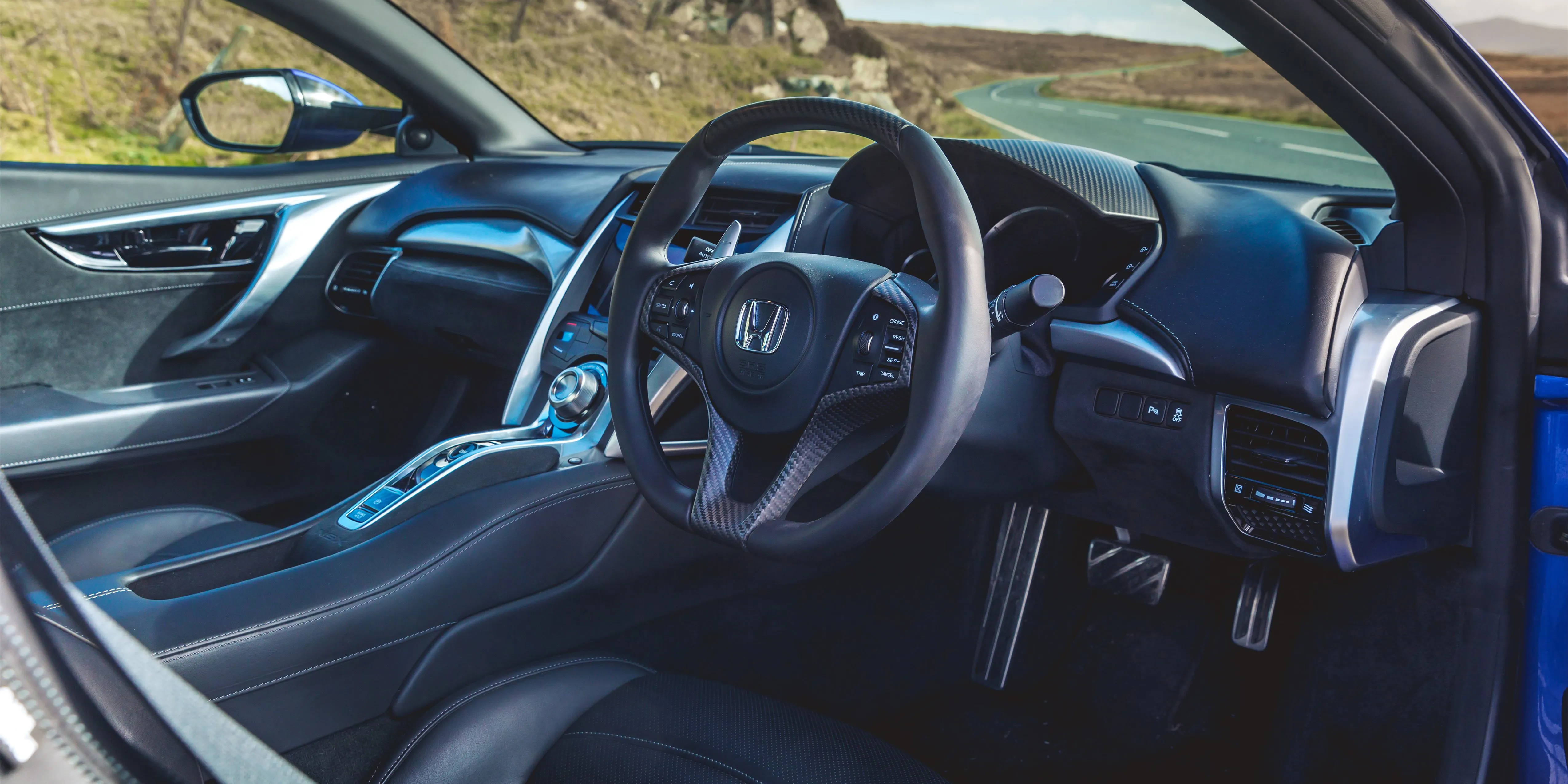 The driver's cockpit of the Honda NSX, featuring leather upholstery and digital display