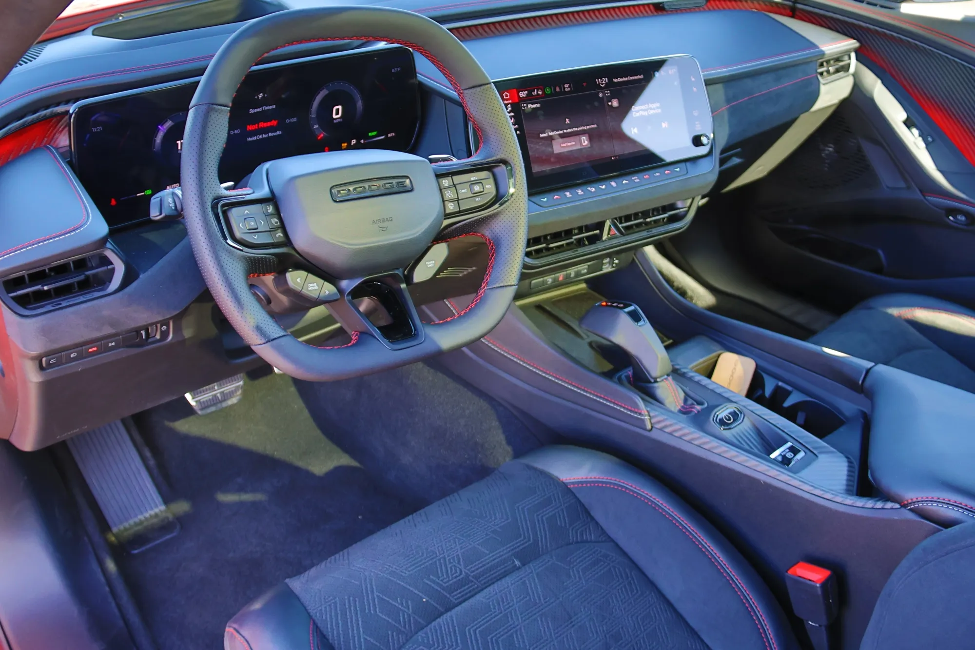 The modern, driver-centric interior cockpit of the 2024 Dodge Charger Daytona, featuring dual digital displays and a traditional pistol-grip shifter.