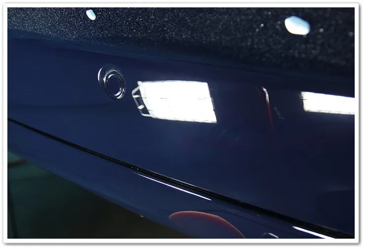 The Rolls Royce Phantom's rear bumper after the compounding stage, exhibiting a deep, clear, and reflective finish with defects visibly reduced.