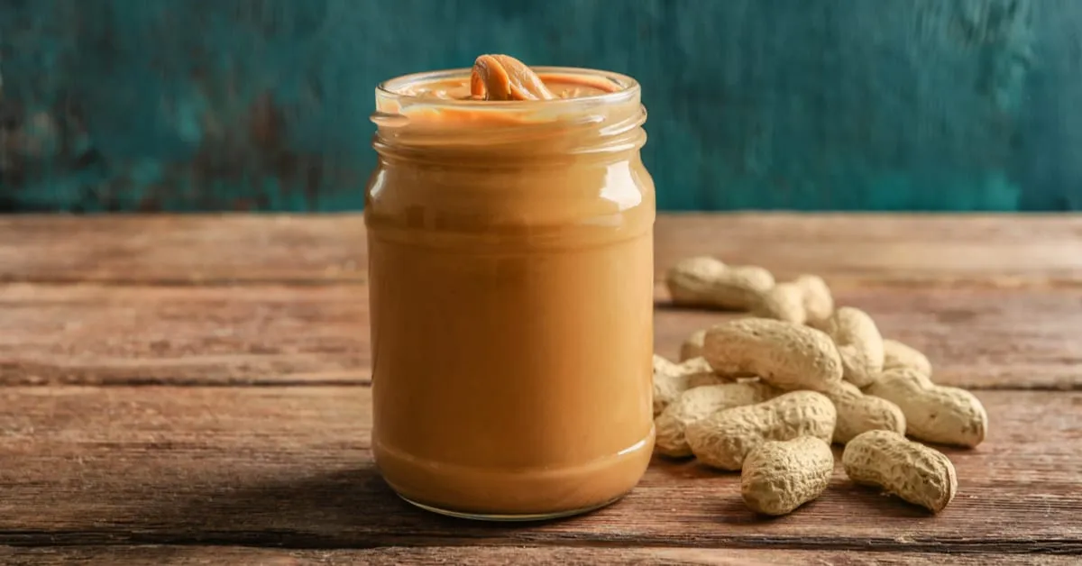 Variety of peanut butter jars on a grocery shelf, some with warnings