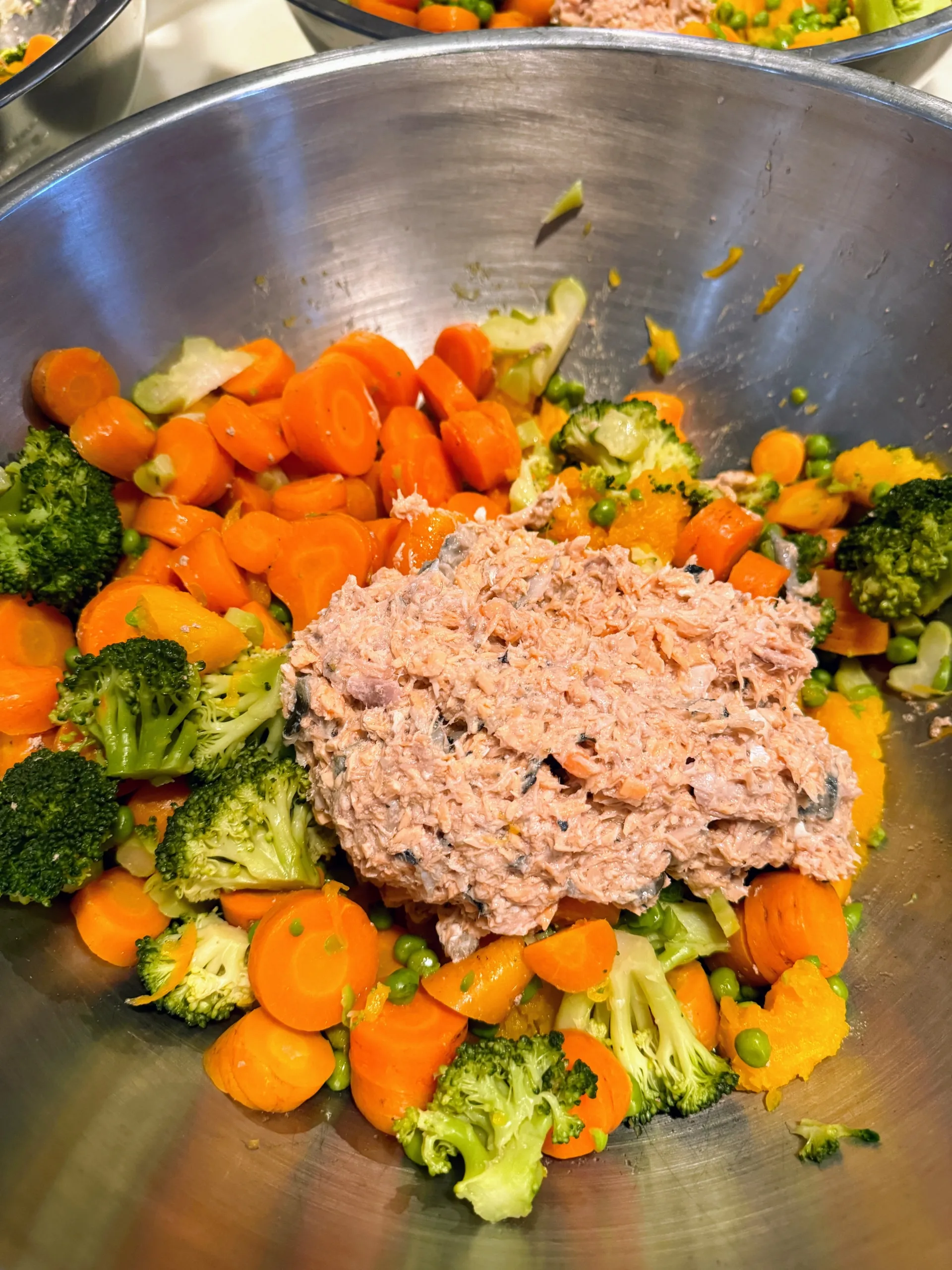 Various cooked dog food ingredients sorted into multiple stainless steel bowls.