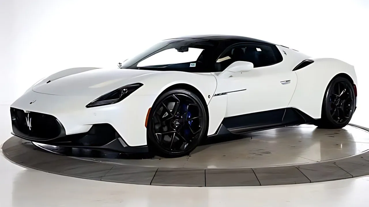 White 2023 Maserati MC20 with black accents on a circular platform in a lit showroom, standout in best supercars under 0k