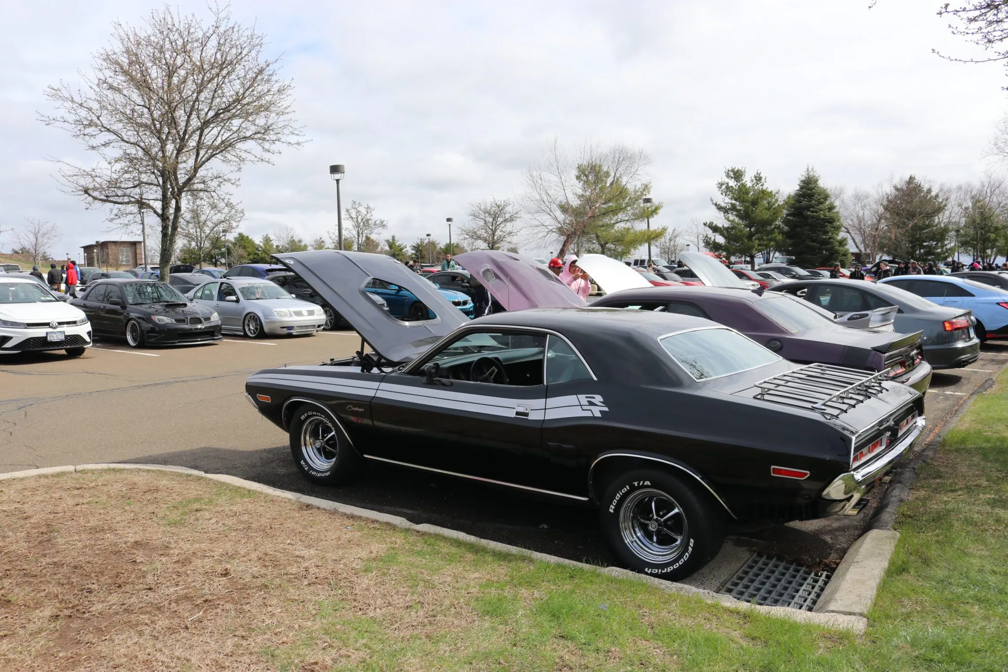 Wide shot of a classic Dodge Challenger parked at a car show, showcasing its distinctive design.