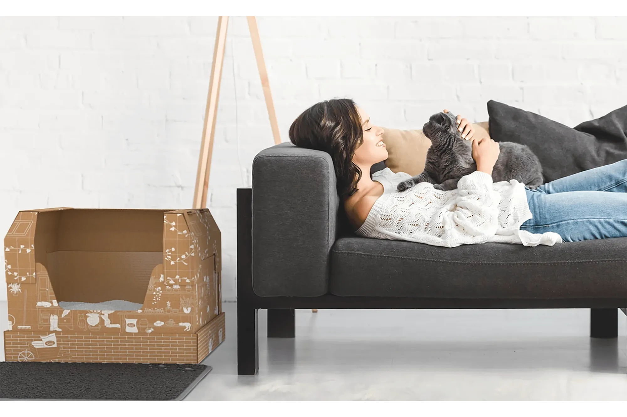 Woman on couch with cat and cardboard litter box