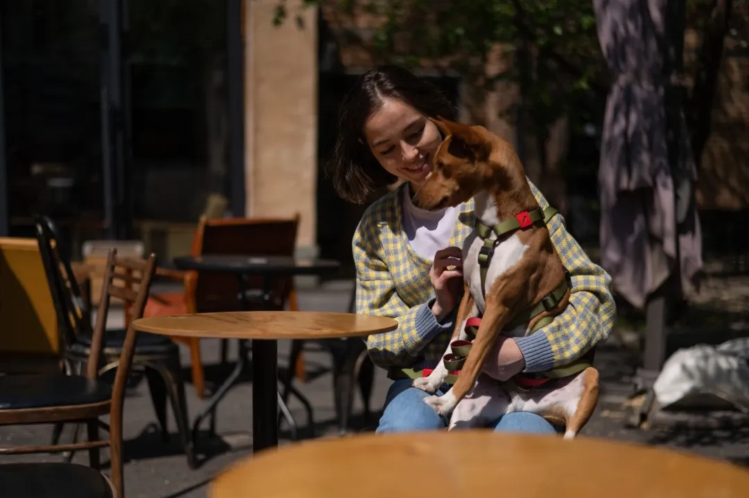 A woman smiling while interacting with her psychiatric service dog in a park.