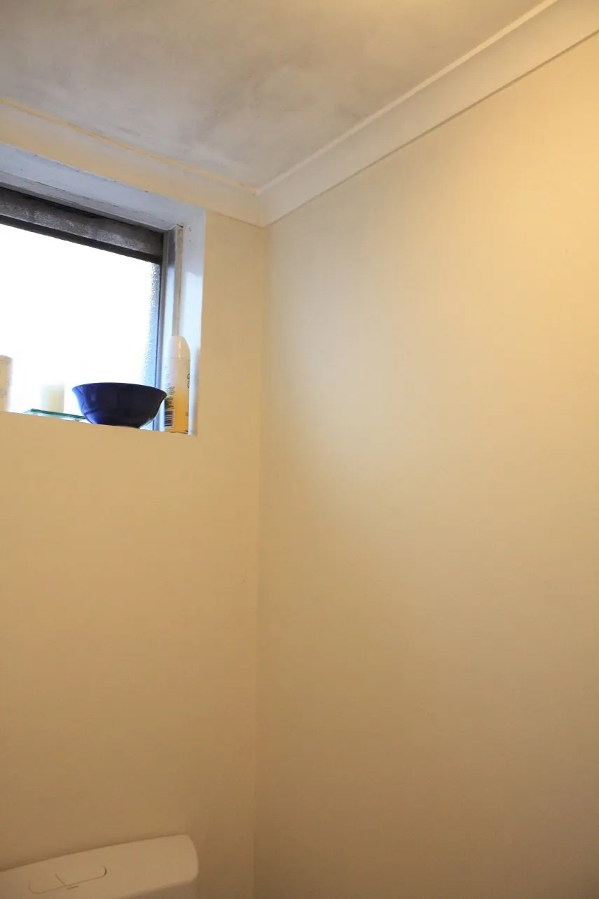 Before and after comparison of a toilet with DIY book page wallpaper.