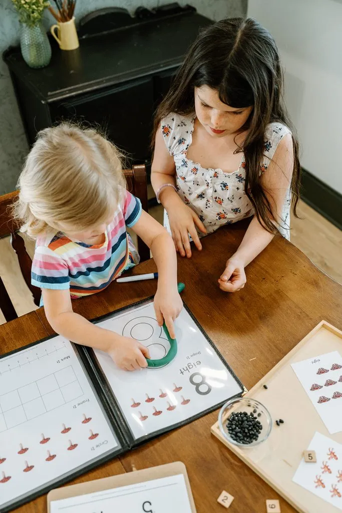 Children practicing number formation on laminated sheets in menu covers