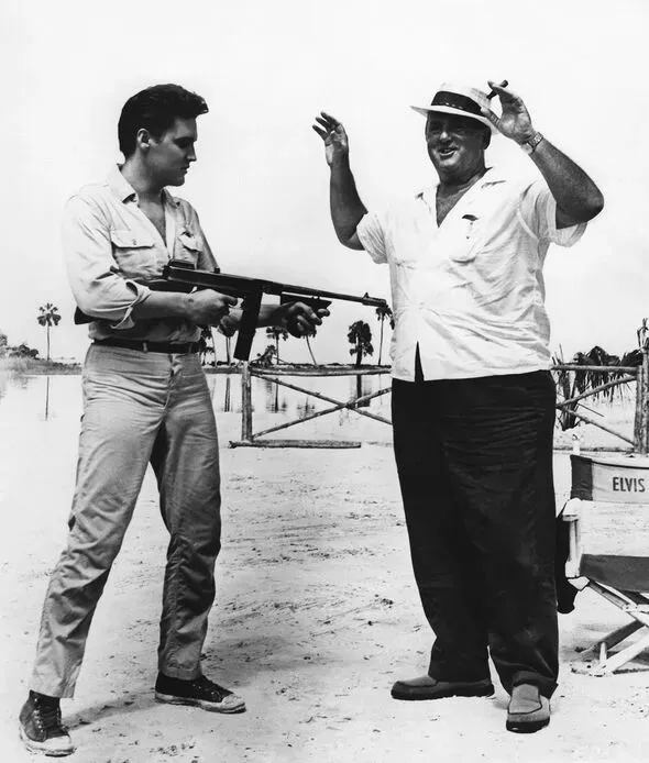 Elvis holding a gun towards Colonel Parker, symbolizing their contentious relationship