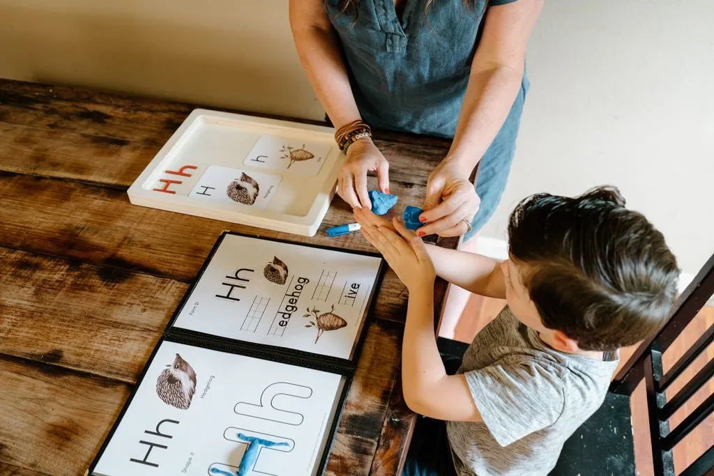 Practicing letter formation with a dry-erase marker in a menu cover