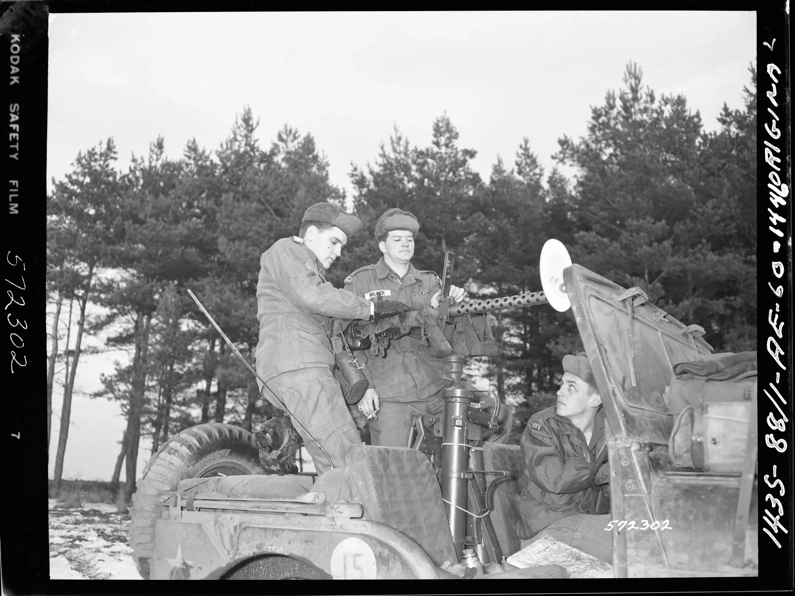 Sgt Elvis Presley, in charge, checks machine gun of the 32nd Armor Scout Jeep during Army’s Winter Shield maneuver in Va Bavaria, West Germany.