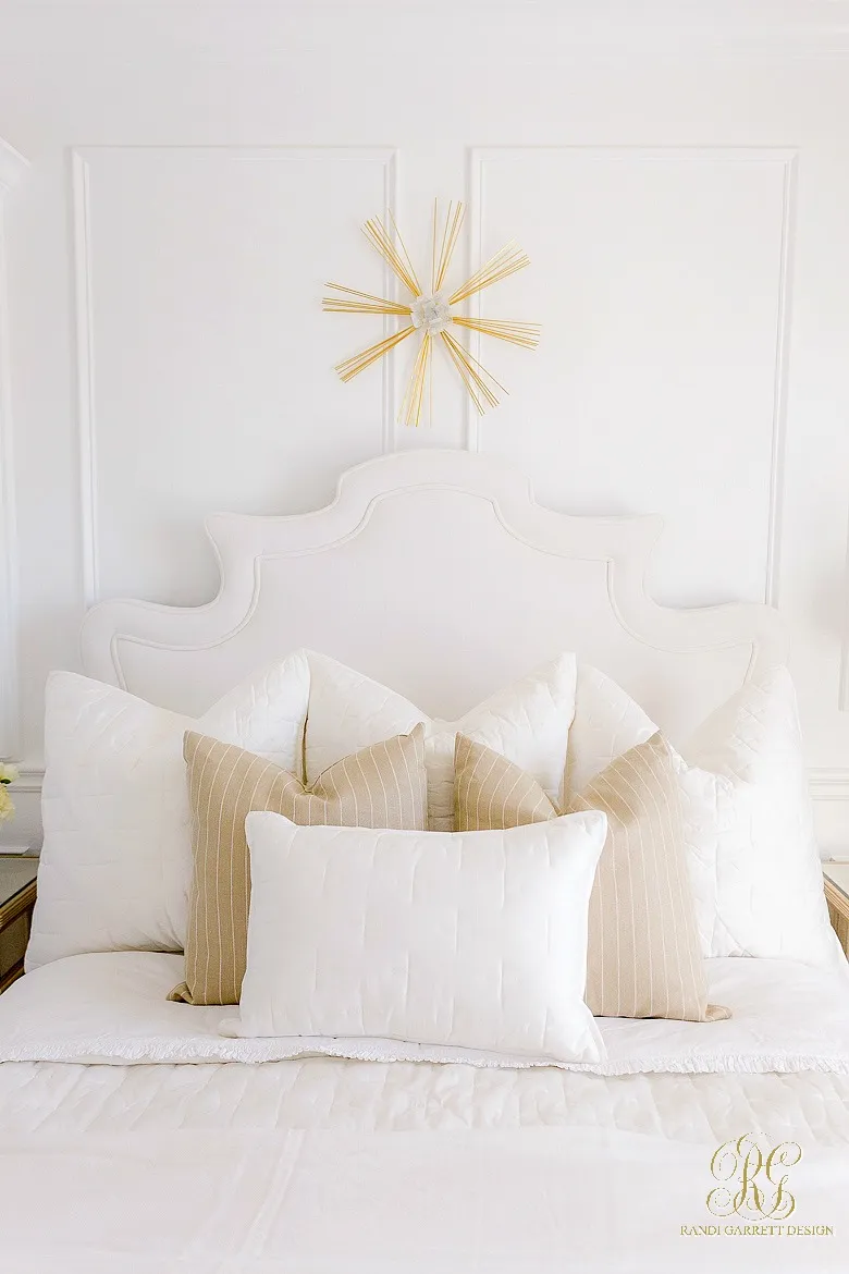 A bed featuring white Euro pillows, striped square pillows, and a lumbar pillow.