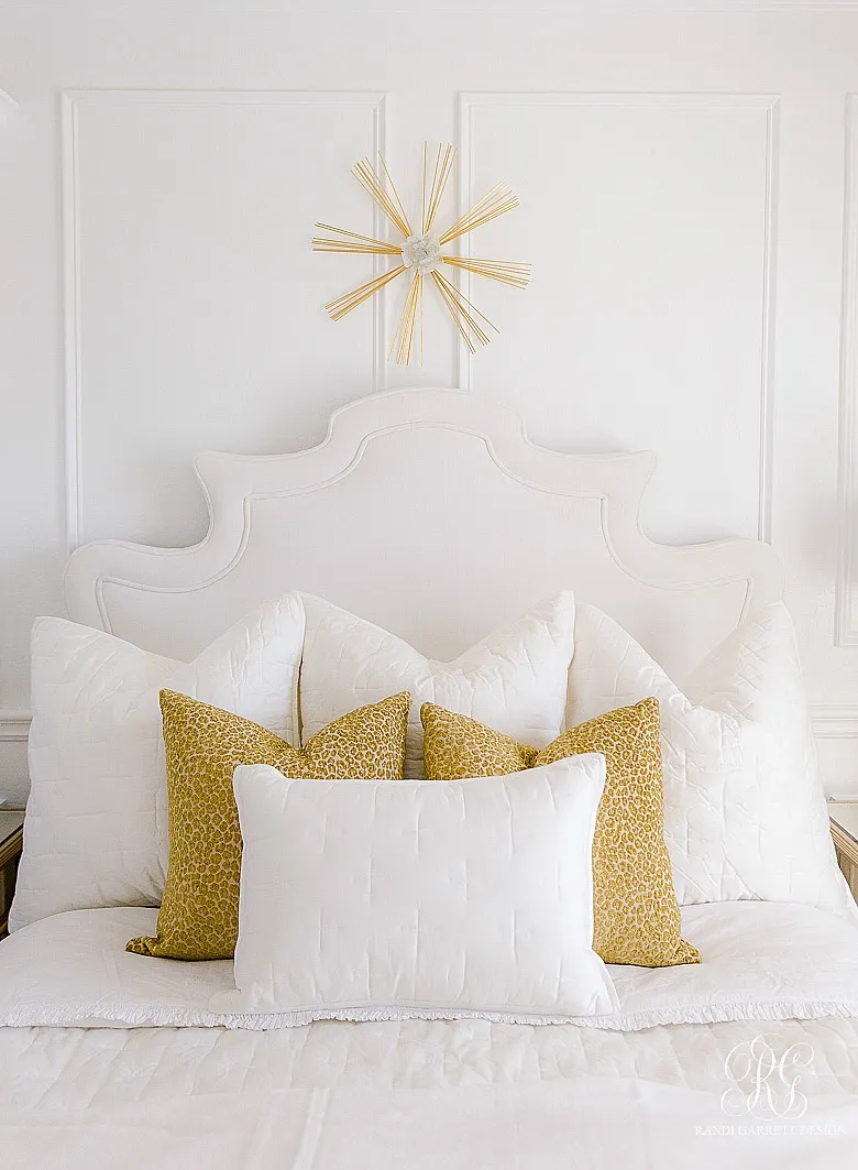 A bed styled with white Euro pillows, leopard print square pillows, and a lumbar pillow.