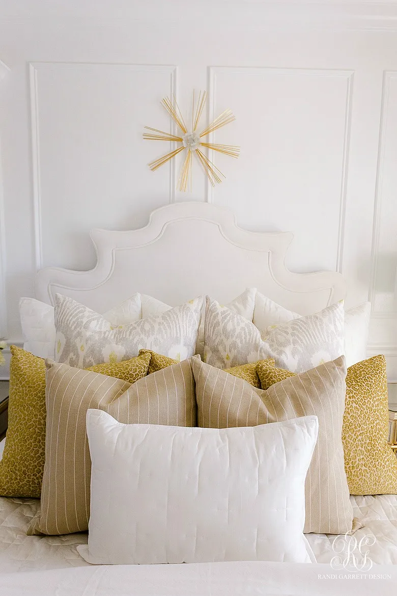 A generously layered bed with a multitude of pillows in different sizes and patterns.
