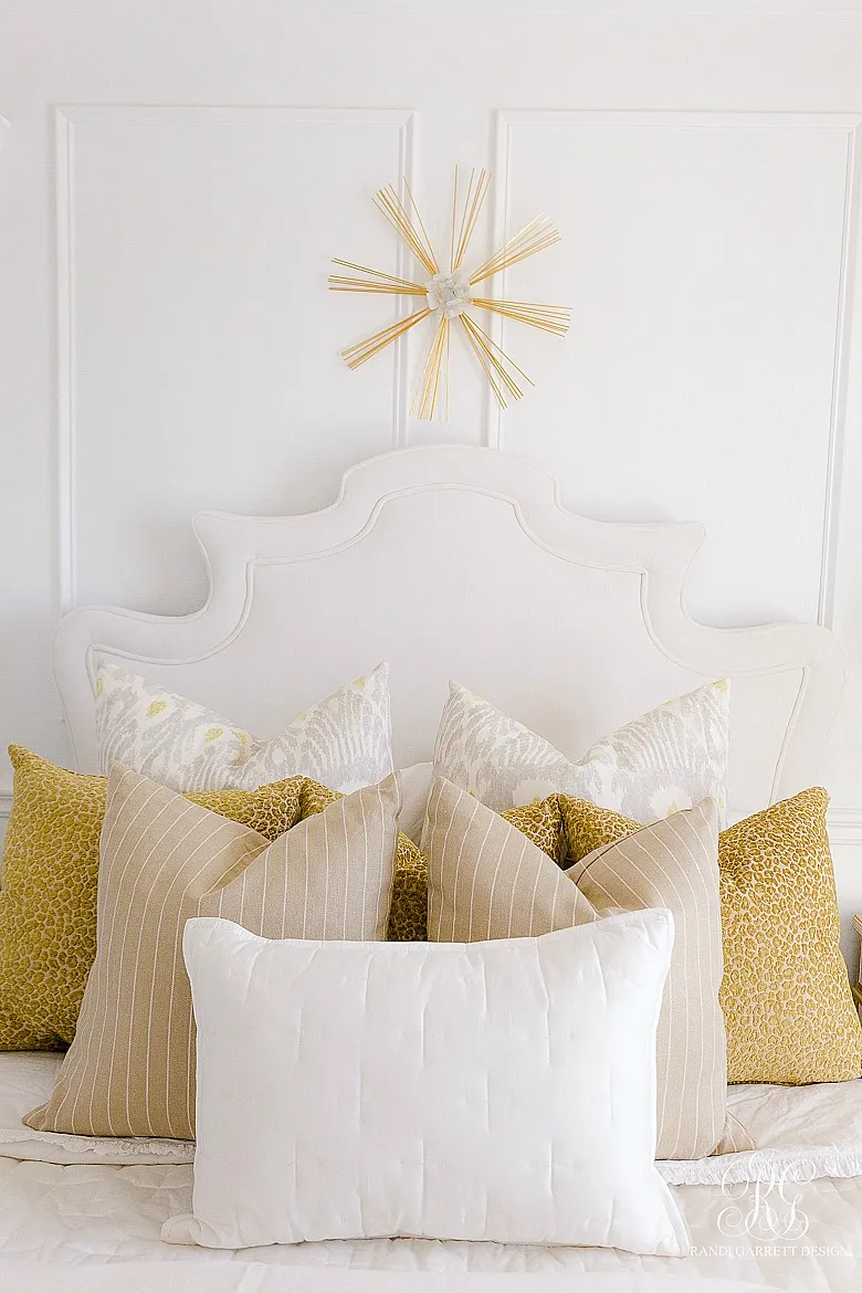 A richly layered bed with multiple patterned pillows in different sizes.