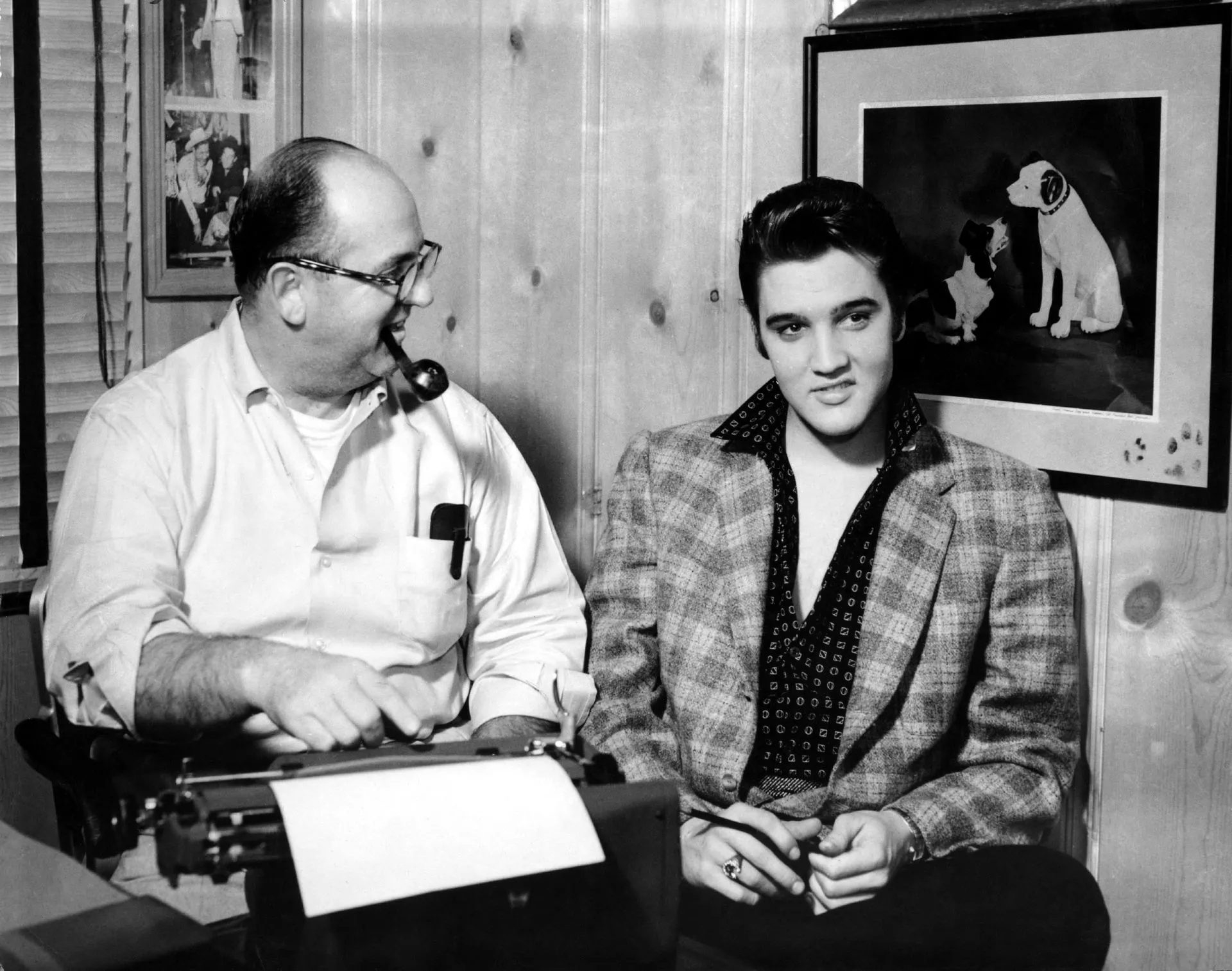Black and white portrait of Elvis Presley standing beside Colonel Tom Parker during his career peak