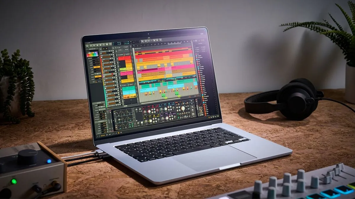 An Apple MacBook Air M4 on a desk with audio interface, headphones, and MIDI controller