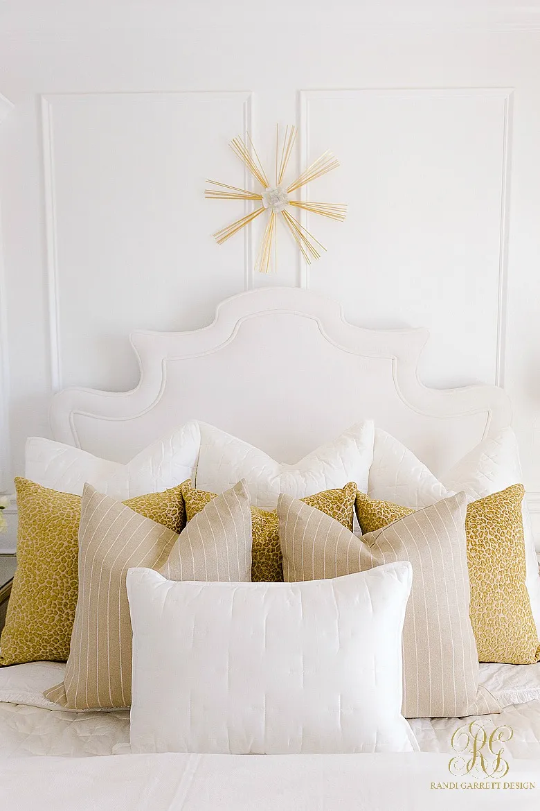 An artfully arranged collection of pillows with varying patterns on a bed.