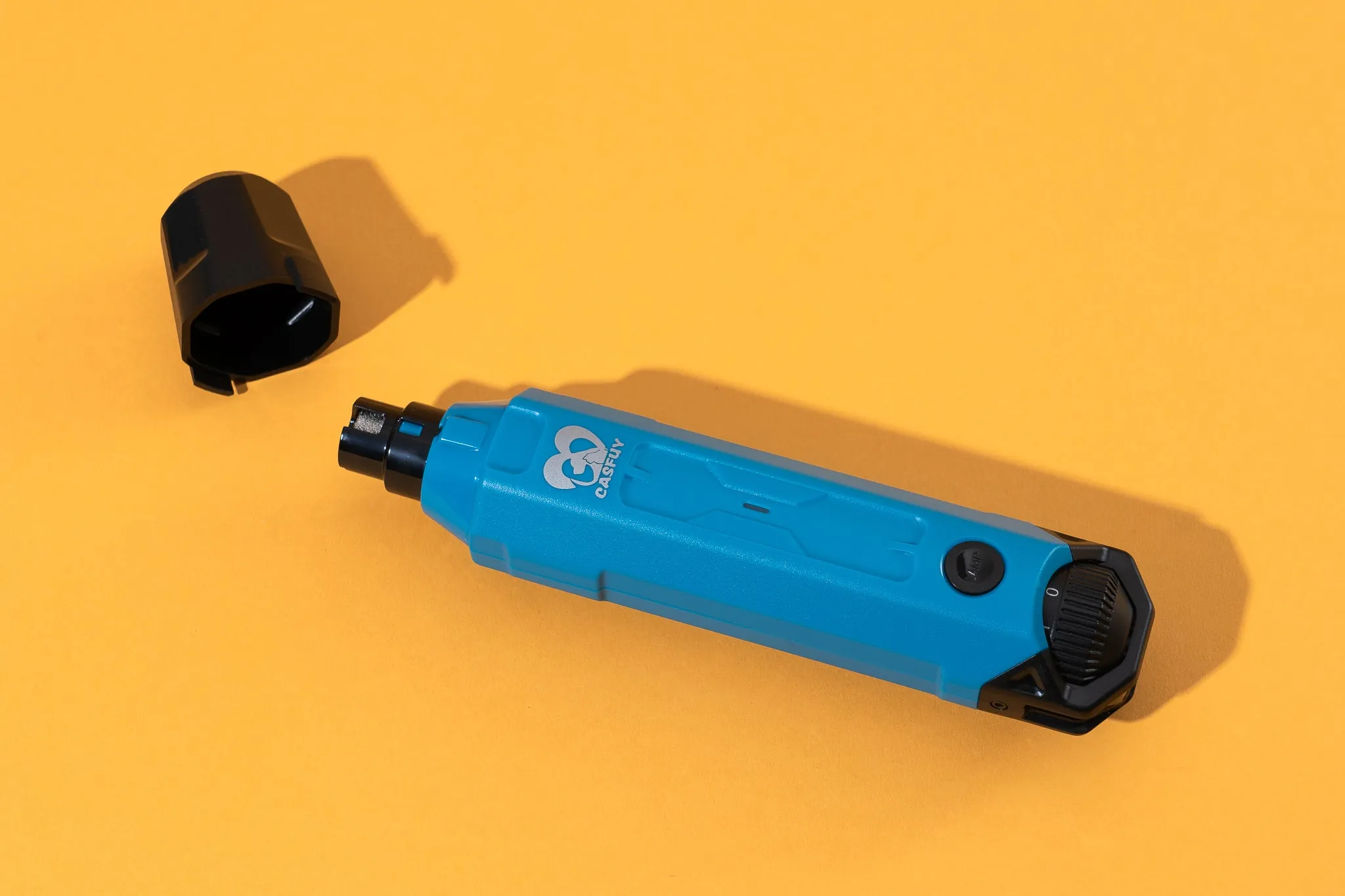 The Casfuy 6-Speed Dog Nail Grinder resting on a yellow background with its cap removed.