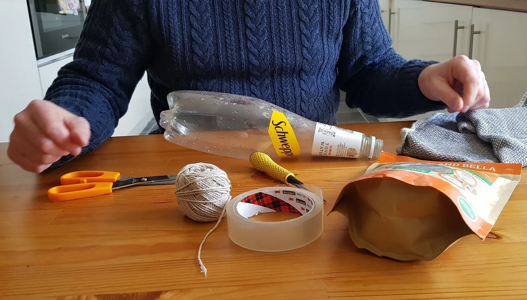 Gathered materials for the Bottle of Treats game, including a plastic bottle, cardboard, scissors, string, tape, and dog treats.