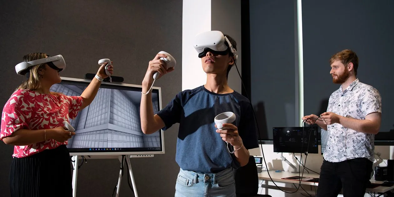 Three students learning VR technologies in a modern classroom setting