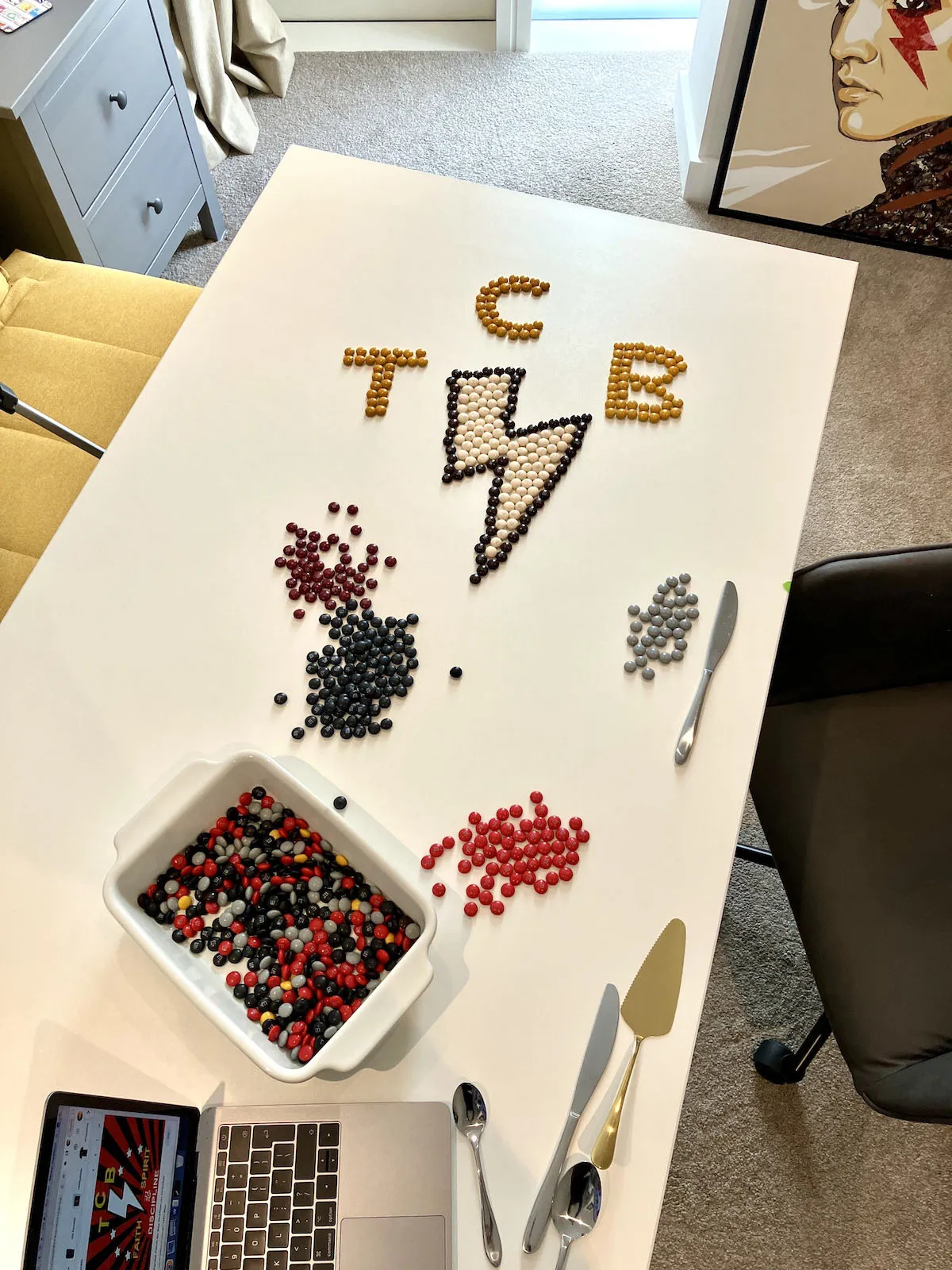 Elvis Presley TCB lightning bolt logo recreated using hundreds of colourful M&Ms chocolates arranged on a flat surface