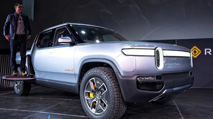 Rivian founder and CEO RJ Scaringe standing on the side access panel of the debut Rivian R1T electric pickup truck