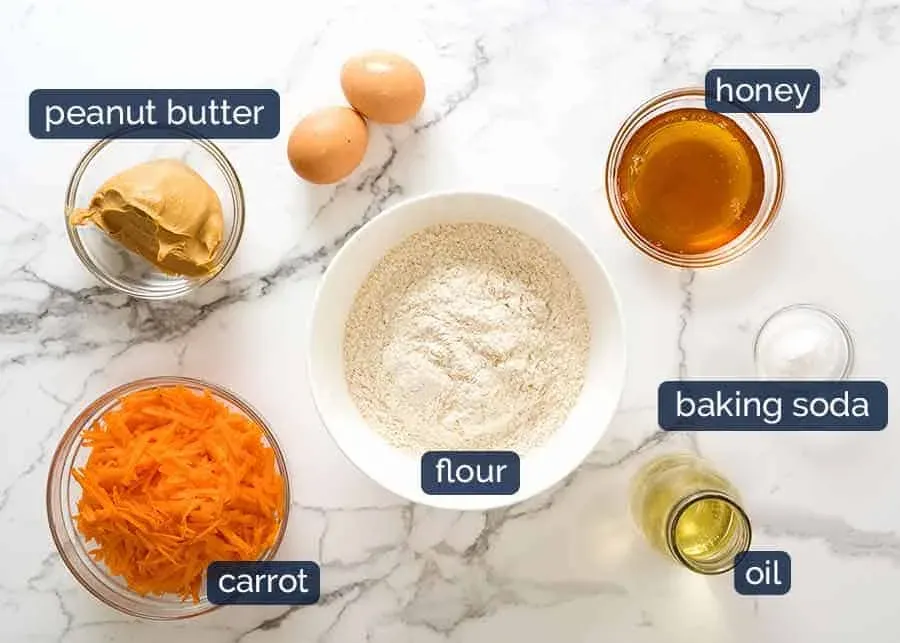 All the wholesome ingredients laid out for the dog birthday cake recipe including carrots, eggs, peanut butter, and flour
