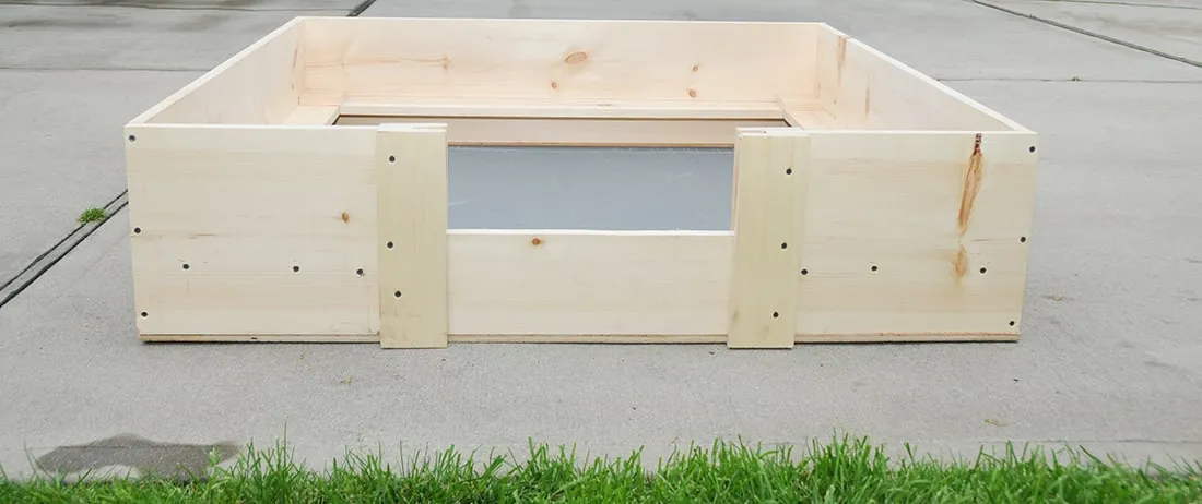 A wooden whelping box prepared with soft bedding for a pregnant dog