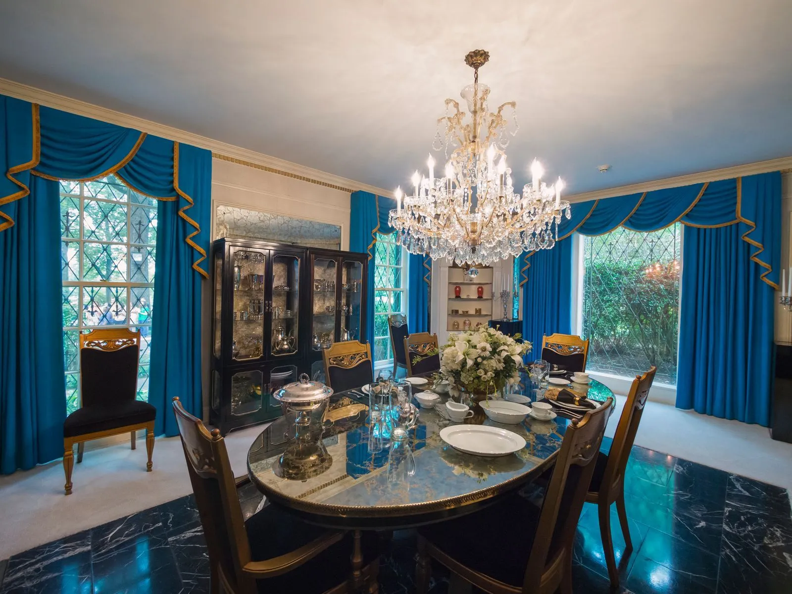 Dining room at Graceland with crystal chandelier and blue curtains