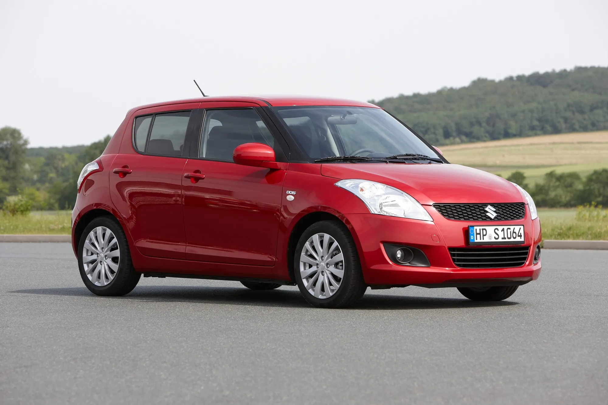 Suzuki Swift parked in an urban setting with sunlight reflecting off the body
